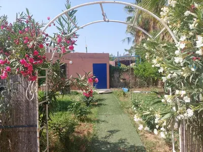 a garden with a blue door and pink flowers at Ferme Amzrou in Had Abdallah Rhiat