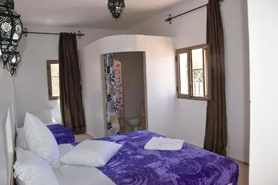 a bedroom with a purple bed with white pillows at Riad Dades Canyon in Akedim Msemrir
