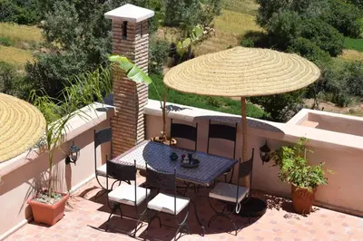a table and chairs under an umbrella on a patio at Riad Dades Canyon in Akedim Msemrir
