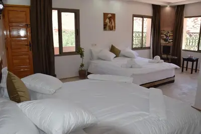 a room with three beds with white sheets at Riad Dades Canyon in Akedim Msemrir