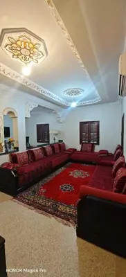 a living room with a couch and a rug at Bel appartement familial au centre ville in El Kelaa des Srarhna