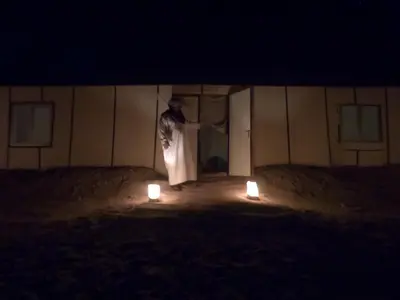 a man standing in front of a building with two lights at Sahara Dream Camp in Oulad Hammou