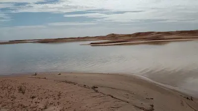 a body of water next to a sandy beach at Sahara Dream Camp in Oulad Hammou