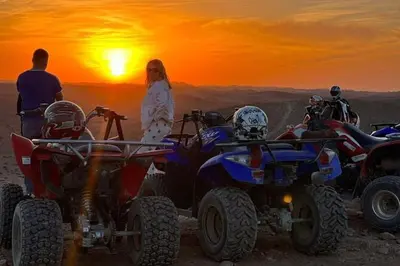 a woman standing next to a group of atvs in the desert at sahara camp in Oulad Akkou