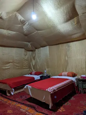 two beds in a room with a ceiling at Merzouga Nomade Desert Camp in Merzouga