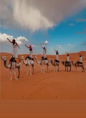 a group of people riding on camels in the desert at Merzouga Nomade Desert Camp in Merzouga