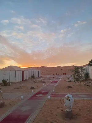 a row of tents in the desert at sunset at Merzouga Nomade Desert Camp in Merzouga