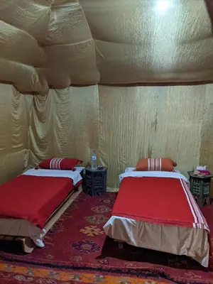 a room with two beds in a tent at Merzouga Nomade Desert Camp in Merzouga