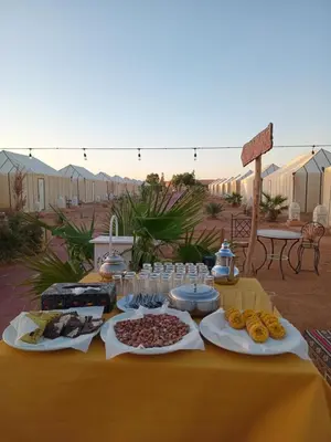 a table with food on a yellow table cloth at Merzouga Nomade Desert Camp in Merzouga