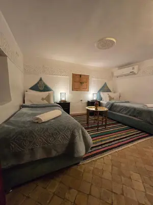 a bedroom with two beds and a table at Riad Mounadim Fes -Authentic Riad Luxury Fes in Fès