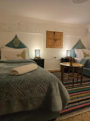 a bedroom with a bed and a couch and a table at Riad Mounadim Fes -Authentic Riad Luxury Fes in Fès