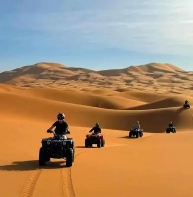 a group of people riding atvs in the desert at jumeirah standard camp merzoug in Merzouga