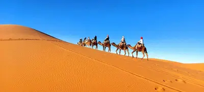 a group of people riding on horses in the desert at jumeirah standard camp merzoug in Merzouga