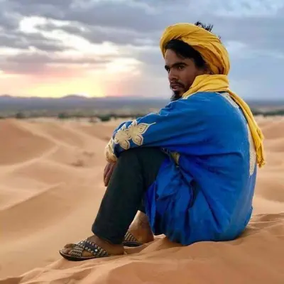 a man sitting on the sand in the desert at jumeirah standard camp merzoug in Merzouga