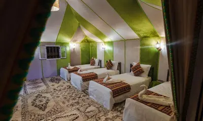 a room with four beds and green walls at Gnaoua Luxury Camp in Merzouga