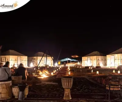 a group of people sitting on a bench at night at Gnaoua Luxury Camp in Merzouga