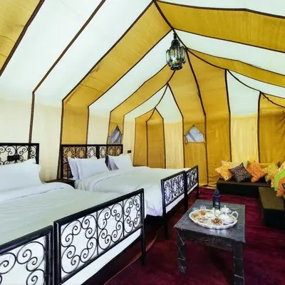 two beds in a room with a tent at Happy luxury camp in Merzouga