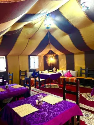 a tent with purple tables and chairs in a room at Happy luxury camp in Merzouga