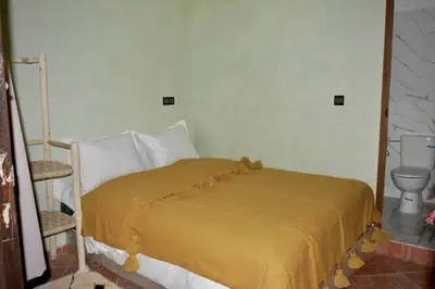 a bedroom with a bed with a yellow blanket on it at Refuge Comfort and Rustic Charm in Anammer
