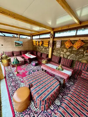 a living room with couches and a stone wall at Under Stars Cozy Moroccan Lodge by Lake Ouiouane in Kasba des Aït Athmane