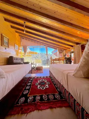 a bedroom with two beds and a rug on the floor at Under Stars Cozy Moroccan Lodge by Lake Ouiouane in Kasba des Aït Athmane