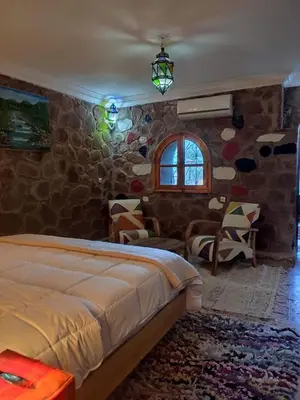 a bedroom with a bed and a stone wall at Auberge laurier rose in Ourika