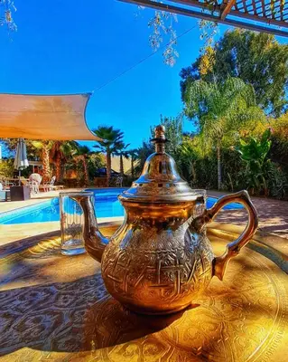 an antique tea pot sitting on a table next to a pool at Dar Muezza in Marrakech