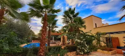 a house with palm trees and a swimming pool at Dar Muezza in Marrakech