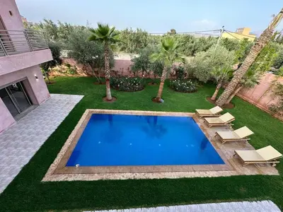 a swimming pool in a yard with palm trees at Villa Bellevue Marrakech in Sbiti