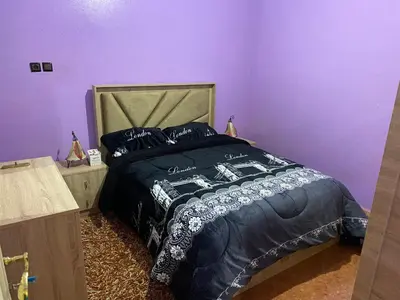 a bedroom with a bed with a purple wall at شقة للكراء اليومي in Azrou