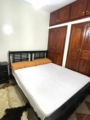 a bed in a room with wooden cabinets at Red Stone Appartement in Midelt