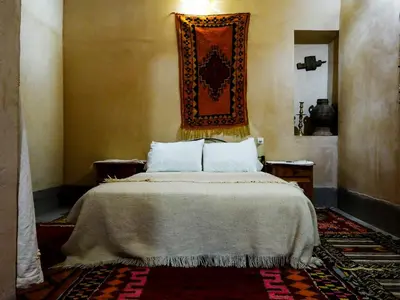a bedroom with a bed and a tapestry on the wall at Dar Tamzdamte Skoura in Skoura