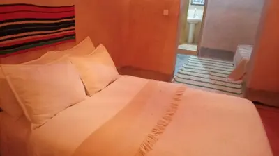 a bed with white sheets and pillows in a room at Dar Tamzdamte Skoura in Skoura
