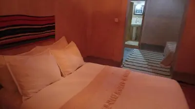 a bed with white sheets and pillows in a room at Dar Tamzdamte Skoura in Skoura