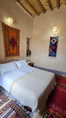 a bedroom with a bed and two pictures on the wall at Dar Tamzdamte Skoura in Skoura