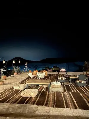 a group of chairs and tables on a beach at night at Marruecos Excursiones Camp in Mezguida