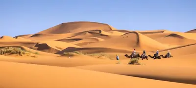 a group of people riding horses in the desert at Marruecos Excursiones Camp in Mezguida