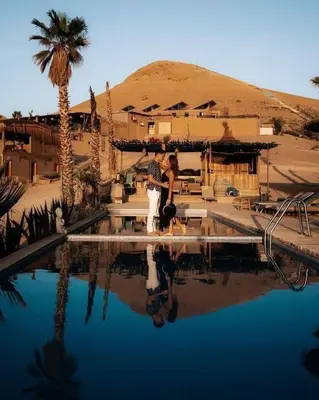 a man and a woman standing next to a swimming pool at Marruecos Excursiones Camp in Mezguida