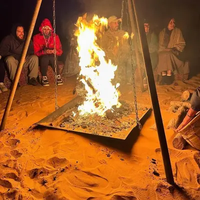 a group of people sitting around a fire at Marruecos Excursiones Camp in Mezguida