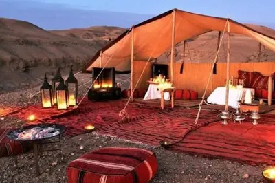 a tent with a bed and a table in the desert at Marruecos Excursiones Camp in Mezguida