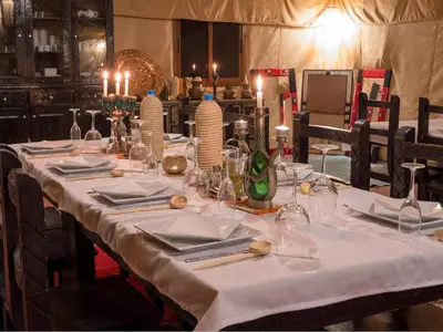 a long table with white table cloth and candles on it at Merzouga Sahara Top Camp in Merzouga