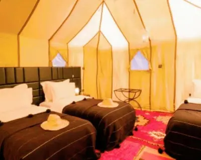 a room with two beds with hats on them at Tipic luxury camp in Merzouga