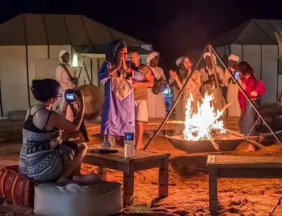 a group of people standing around a fire at Tipic luxury camp in Merzouga