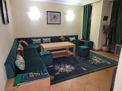 a living room with a green couch and a table at Chalet Haut standing pour les familles seulement in Ifrane