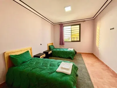 a bedroom with a green bed and a couch at Complexe Kariat Ayoub in Aït Zat