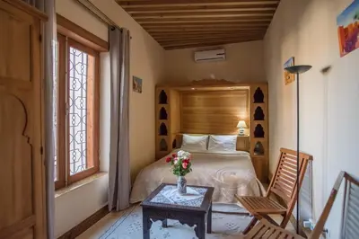 a bedroom with a bed and a table with a vase of flowers at Dar Essoaoude - Fes Nejjarine in Fès