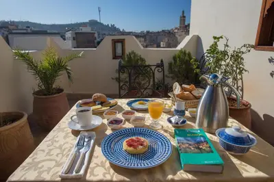 a table with breakfast food on top of a balcony at Dar Essoaoude - Fes Nejjarine in Fès