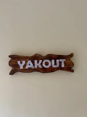 a wooden sign with the word vaughn on a wall at Dyafat Abla in Ouarzazate