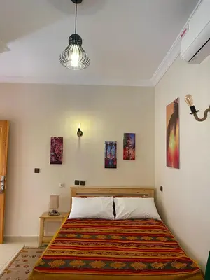 a bedroom with a bed and some pictures on the wall at Dyafat Abla in Ouarzazate