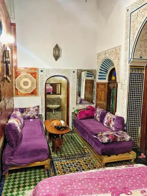 a living room with purple beds and a table at Dar lmallouki in Meknès